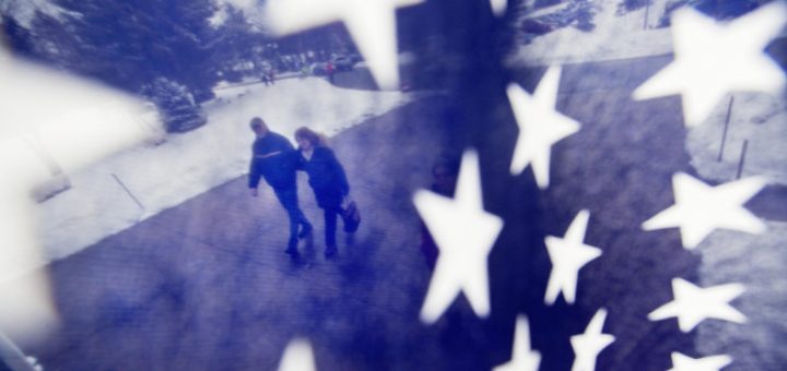 A couple is seen through an American flag as they walk to a polling place for the New Hampshire primary, Tuesday, Feb. 9, 2016, in Nashua, N.H.